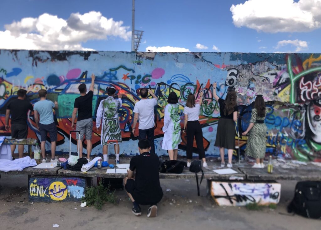 Firmenevent zusammen Graffiti an Mauer sprühen- Teambuilding